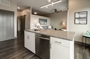 A modern kitchen with a granite countertop and stainless steel appliances.